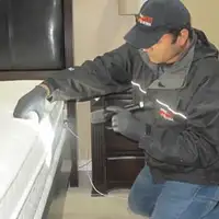 Bed bug inspection technician checking a mattress and bed frame for signs of infestation in Oklahoma City, OK