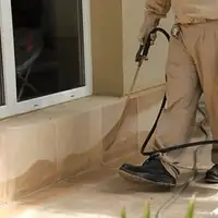 General pest control technician spraying exterior perimeter around a home in Oklahoma City, OK
